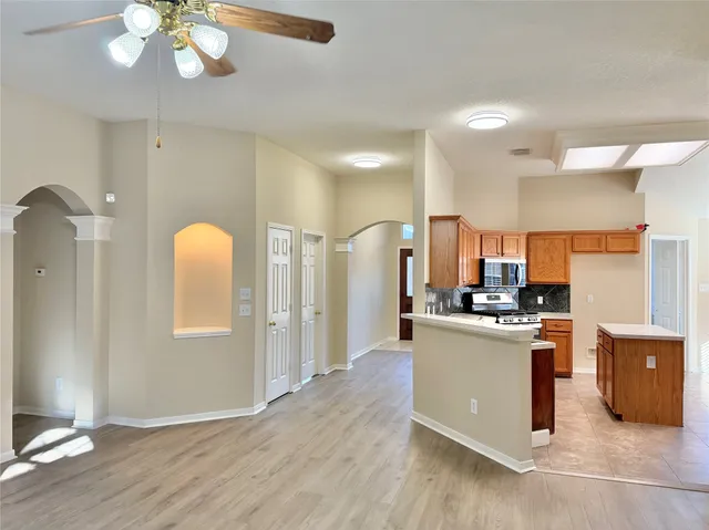 a kitchen with stainless steel appliances granite countertop a refrigerator a stove a sink and white cabinets with wooden floor