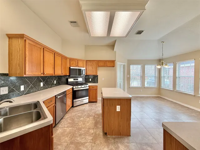 a large kitchen with stainless steel appliances kitchen island granite countertop a sink and cabinets