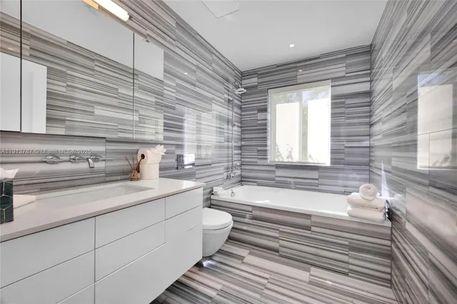 a bathroom with a granite countertop sink mirror and a bathtub