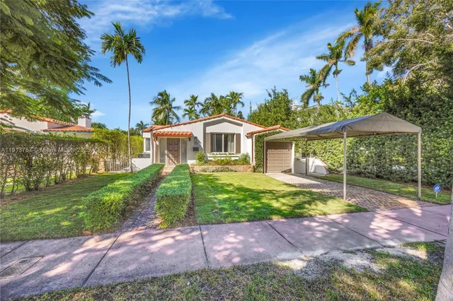 a front view of a house with a yard and potted plants