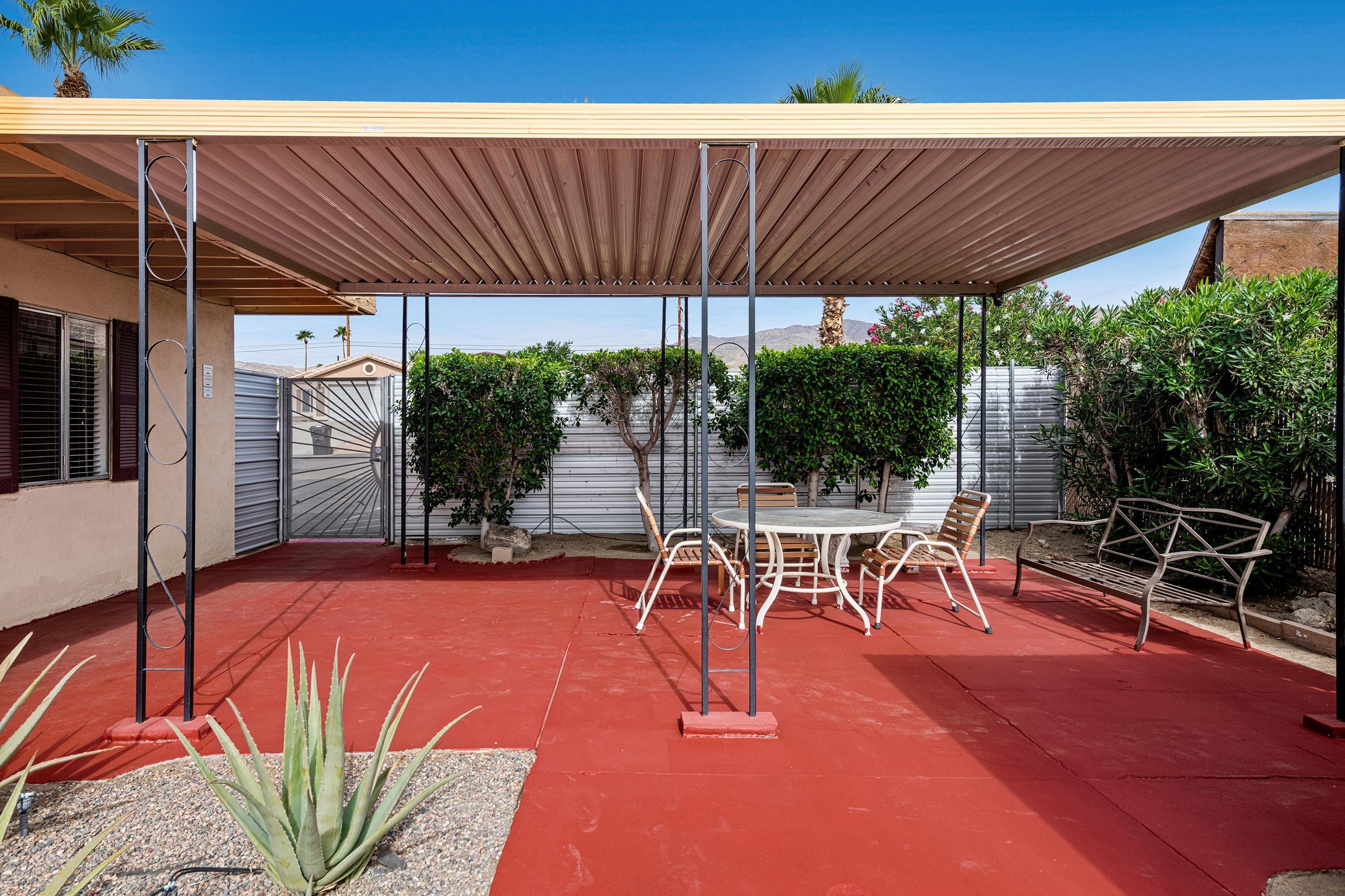 66665 First Street Desert Hot Springs, CA 92240 - Photo 12 of 35 a view of a patio with table and chairs potted plants with wooden floor and fence