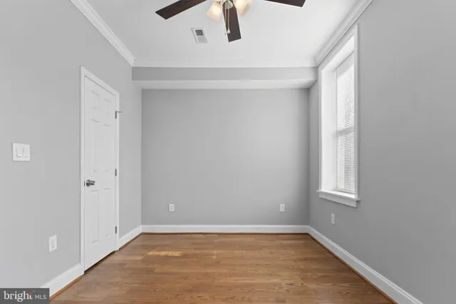 a view of an empty room with window and wooden floor