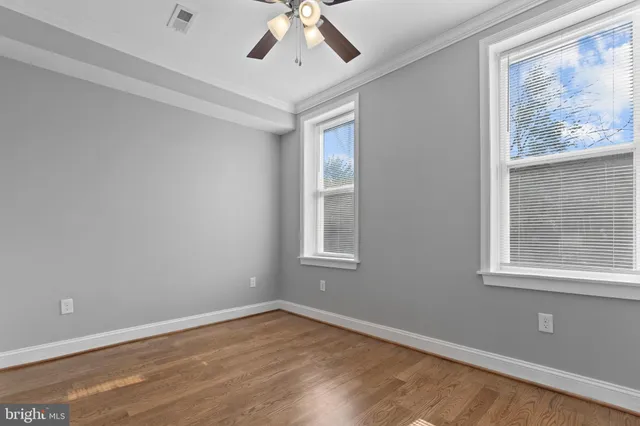 a view of an empty room with a window and wooden floor