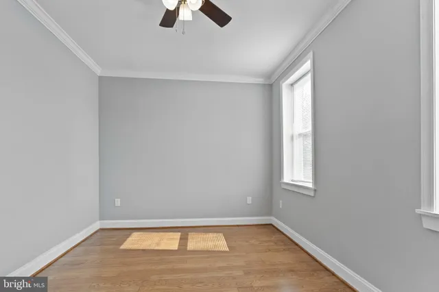 an empty room with chandelier fan and windows