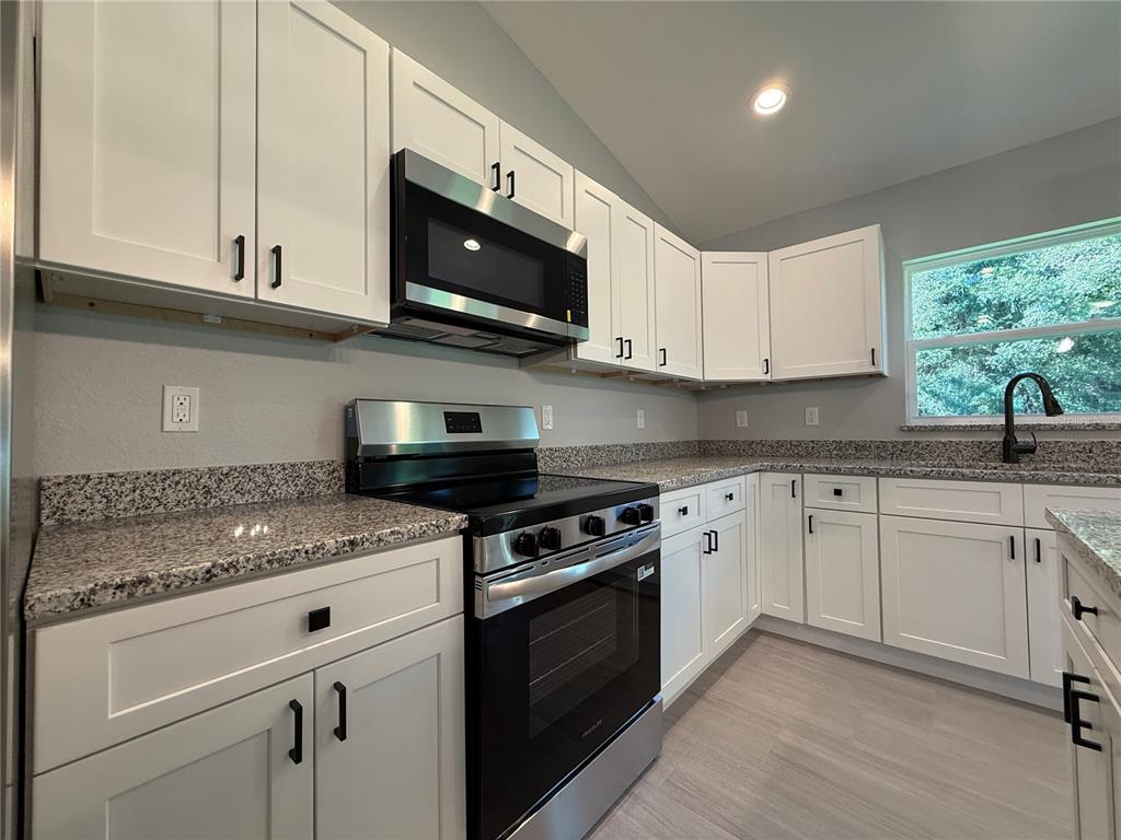 20500 Southwest 54th Street Dunnellon, FL 34431 - Photo 12 of 27 a kitchen with stainless steel appliances granite countertop white cabinets granite counter tops and a window