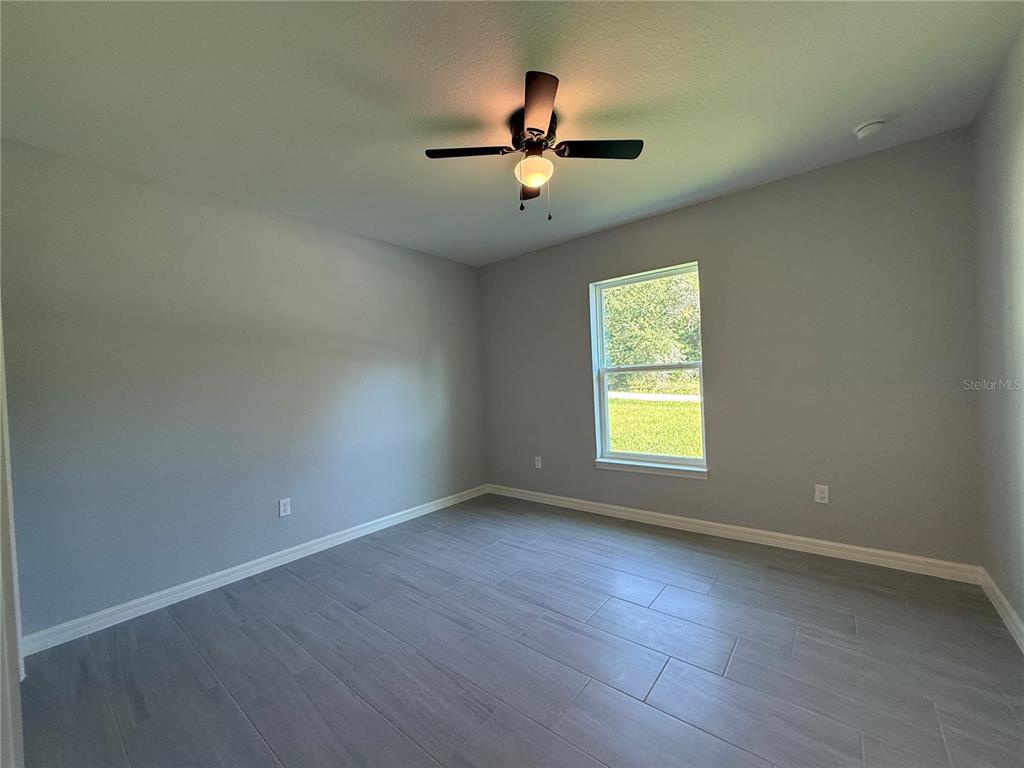20500 Southwest 54th Street Dunnellon, FL 34431 - Photo 4 of 27 an empty room with wooden floor ceiling fan and windows