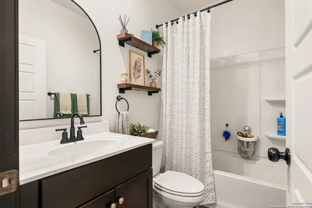a bathroom with a sink a toilet a mirror and shower