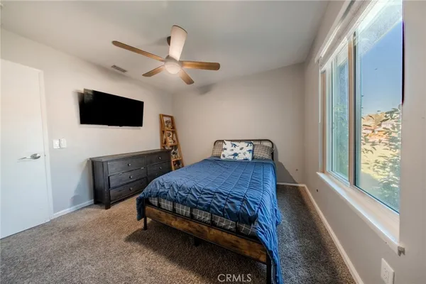 a bedroom with a bed a flat screen tv and a window
