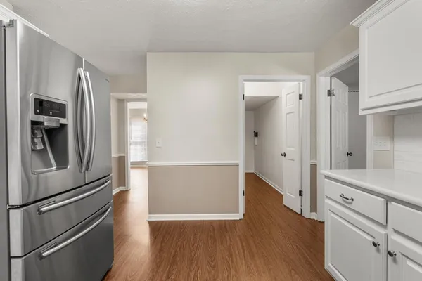 a kitchen with a refrigerator and a wooden floor