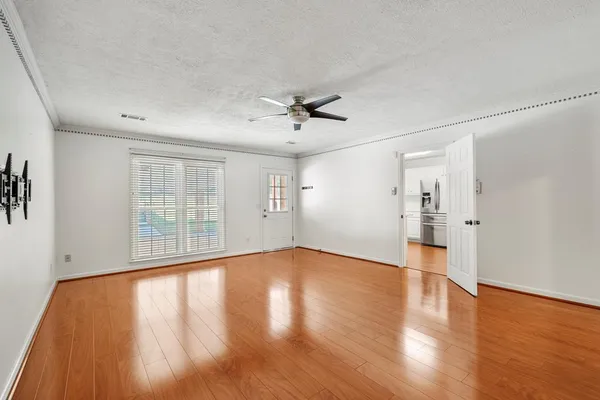 an empty room with wooden floor and windows