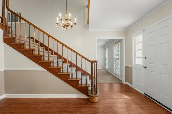 a view of staircase with wooden floor and a chandelier