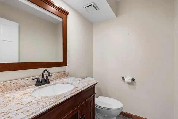 a bathroom with a granite countertop sink a toilet and a mirror
