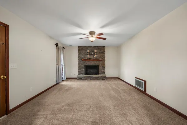 an empty room with fireplace and a ceiling fan