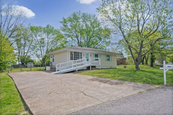 a view of a house with a yard and large tree