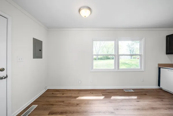an empty room with wooden floor and windows