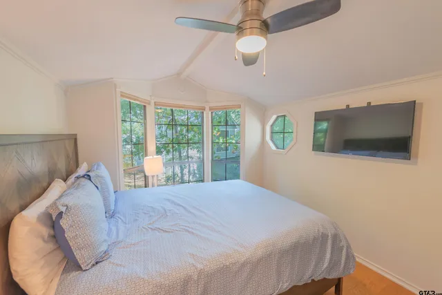 a bedroom with a large bed and a flat tv screen on dresser