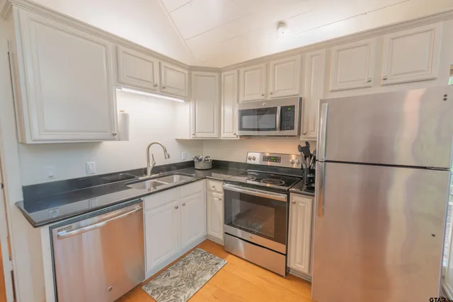 a kitchen with stainless steel appliances granite countertop a refrigerator sink and stove