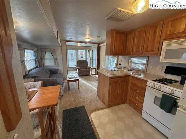 a kitchen with stainless steel appliances granite countertop a stove top oven a sink a dining table and chairs with wooden floor