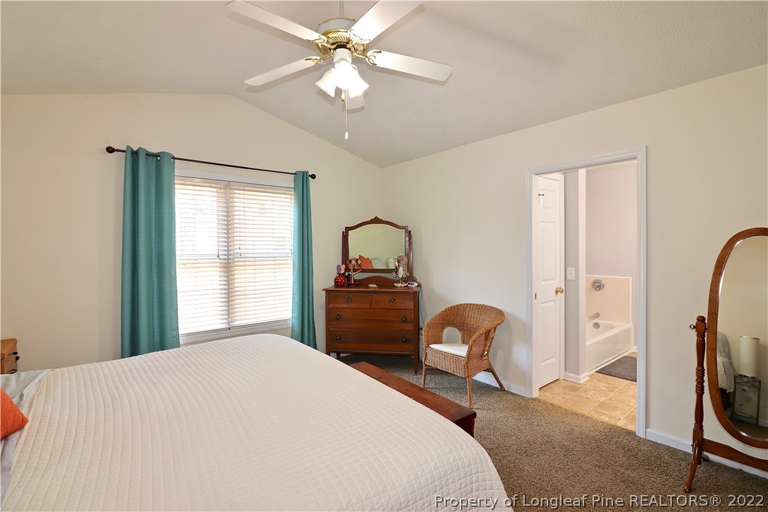 25 Fox Run Road Pinehurst, NC 28374 - Photo 15 of 28 a bedroom with a bed and a chandelier