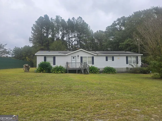 a front view of house with yard and trees in the background