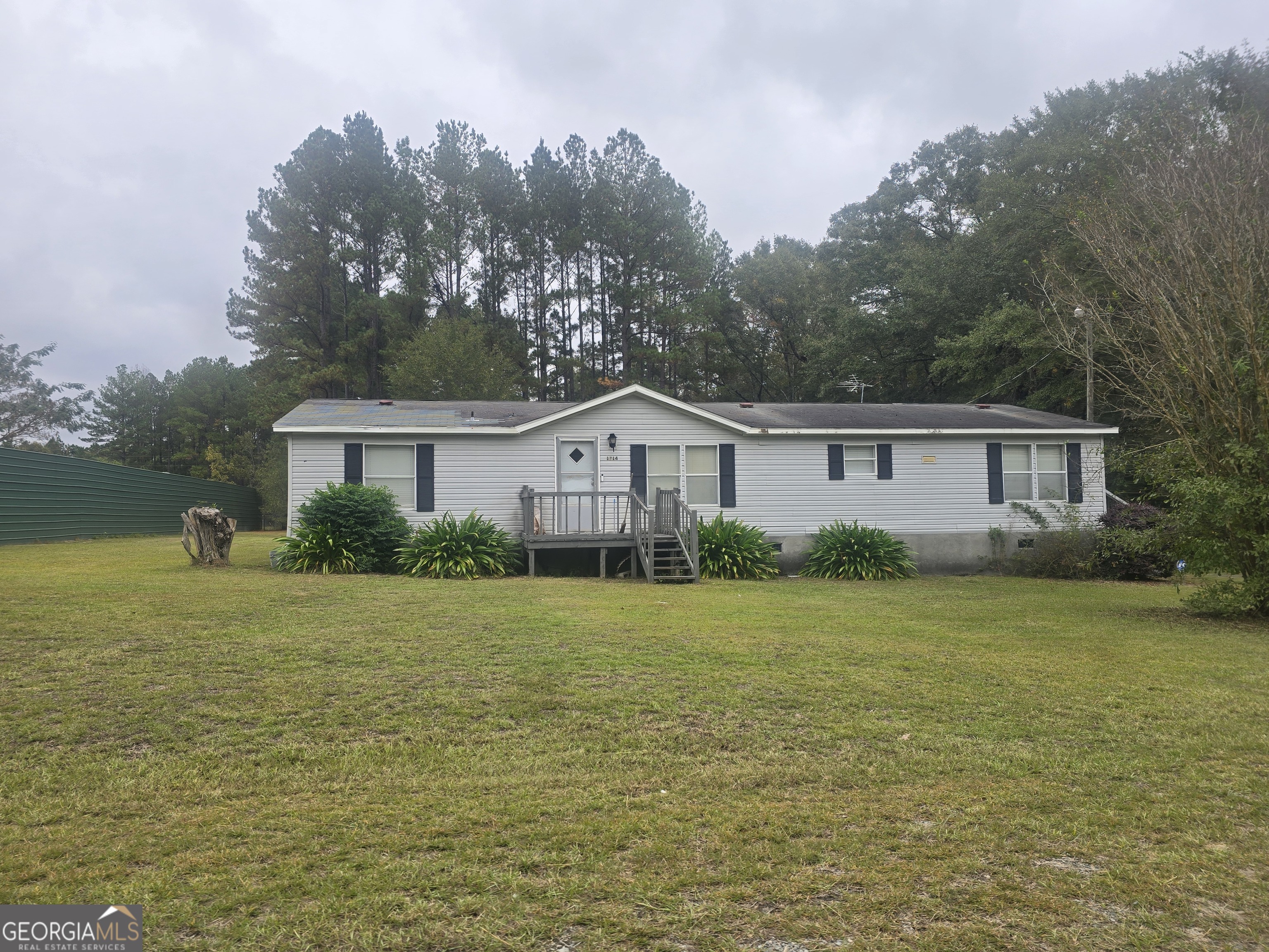 a front view of house with yard and trees in the background