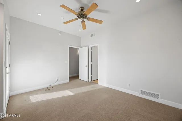 an empty room with a ceiling fan and wooden floor