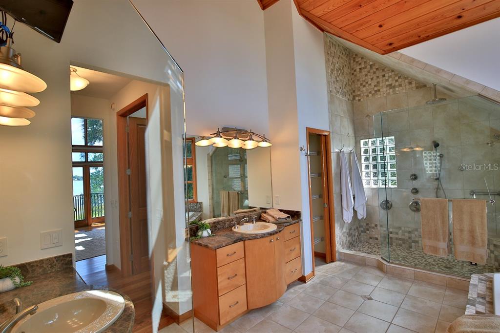 11035 Southeast Sunset Harbor Road Summerfield, FL 34491 - Photo 34 of 97 a spacious bathroom with a granite countertop sink a toilet a mirror and shower