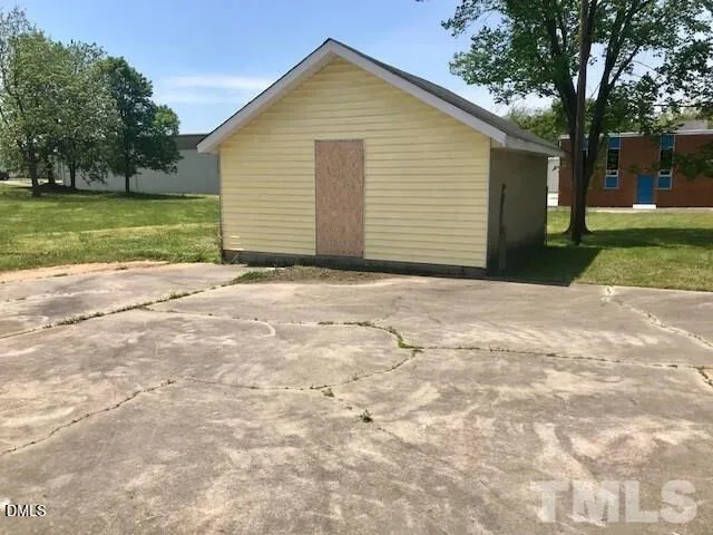 a view of yellow house with a yard and trees