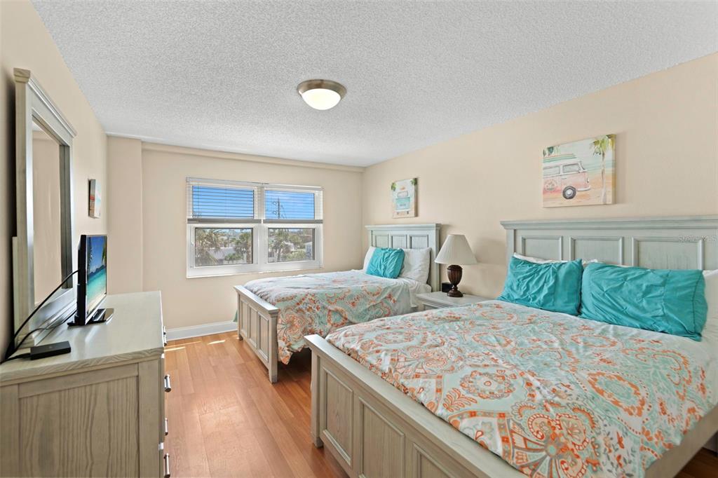 13440 Gulf Lane, Unit 202 Madeira Beach, FL 33708 - Photo 13 of 41 a bedroom with a bed and a flat tv screen on dresser