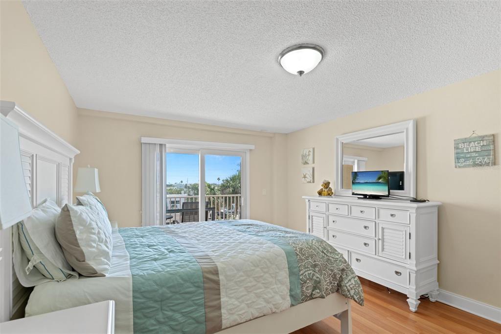 13440 Gulf Lane, Unit 202 Madeira Beach, FL 33708 - Photo 19 of 41 a bedroom with a large bed and a flat tv screen on dresser
