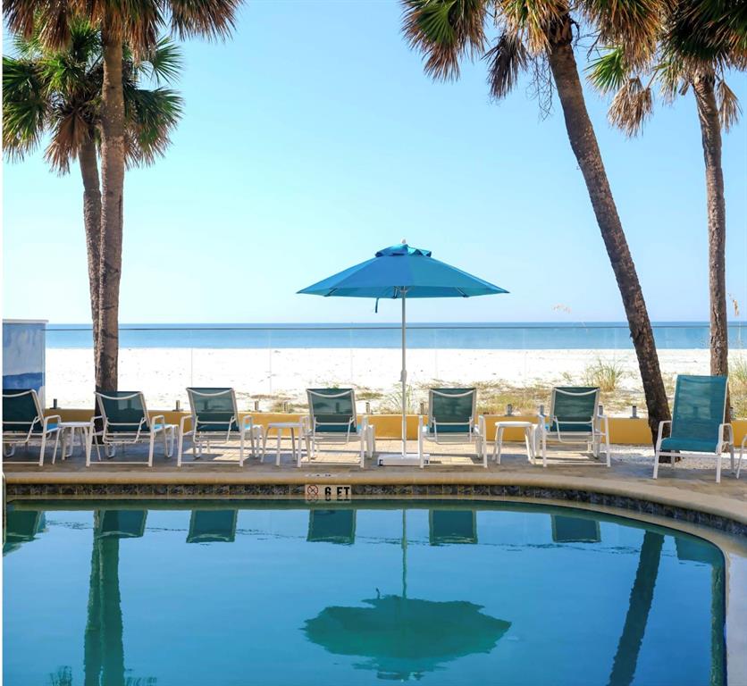 13440 Gulf Lane, Unit 202 Madeira Beach, FL 33708 - Photo 35 of 41 a view of swimming pool with table and chairs under an umbrella
