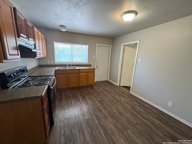 a kitchen with granite countertop a sink and a stove top oven