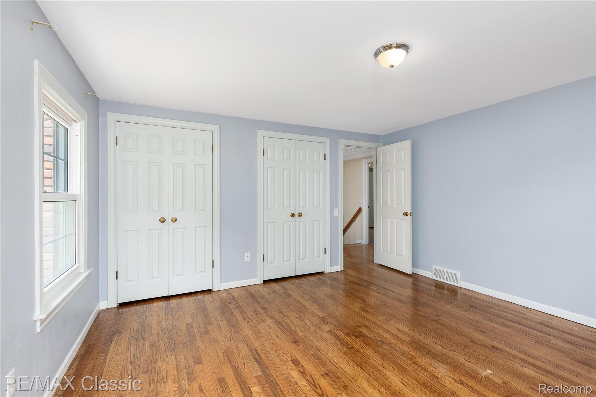 4268 Covered Bridge Road Bloomfield Hills, MI 48302 - Photo 17 of 35 Bright room featuring wood-finish flooring, light blue walls, two double-door closets, and a single window with white trim