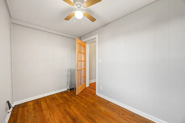 an empty room with wooden floor closet and windows