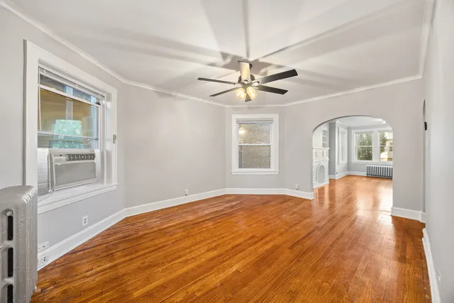 a view of an empty room with a window and wooden floor