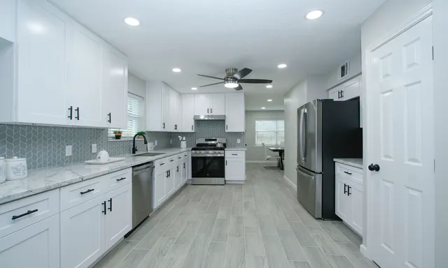 a large kitchen with stainless steel appliances granite countertop a lot of counter space and wooden floor