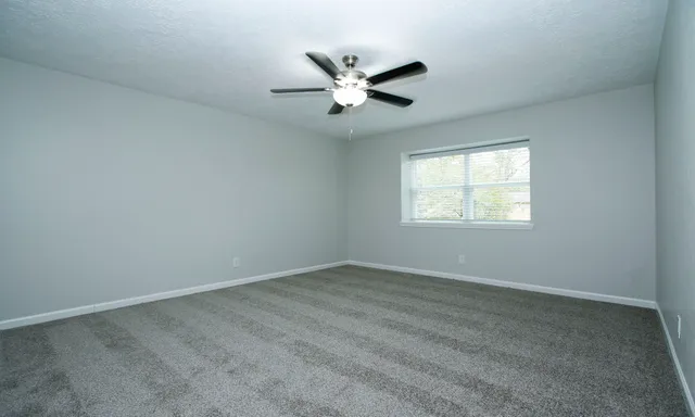 an empty room with window and ceiling fan