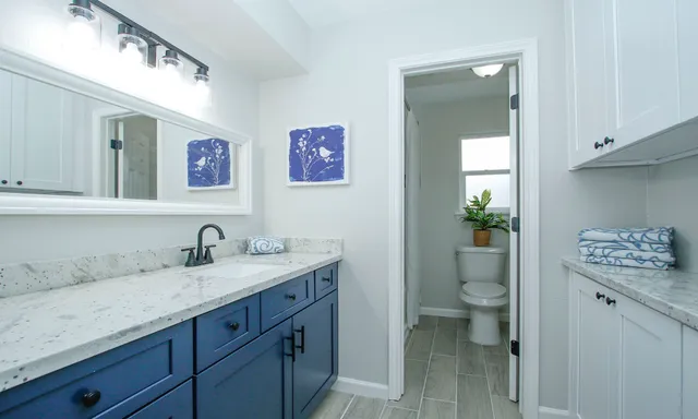 a bathroom with a granite countertop sink a toilet and a mirror