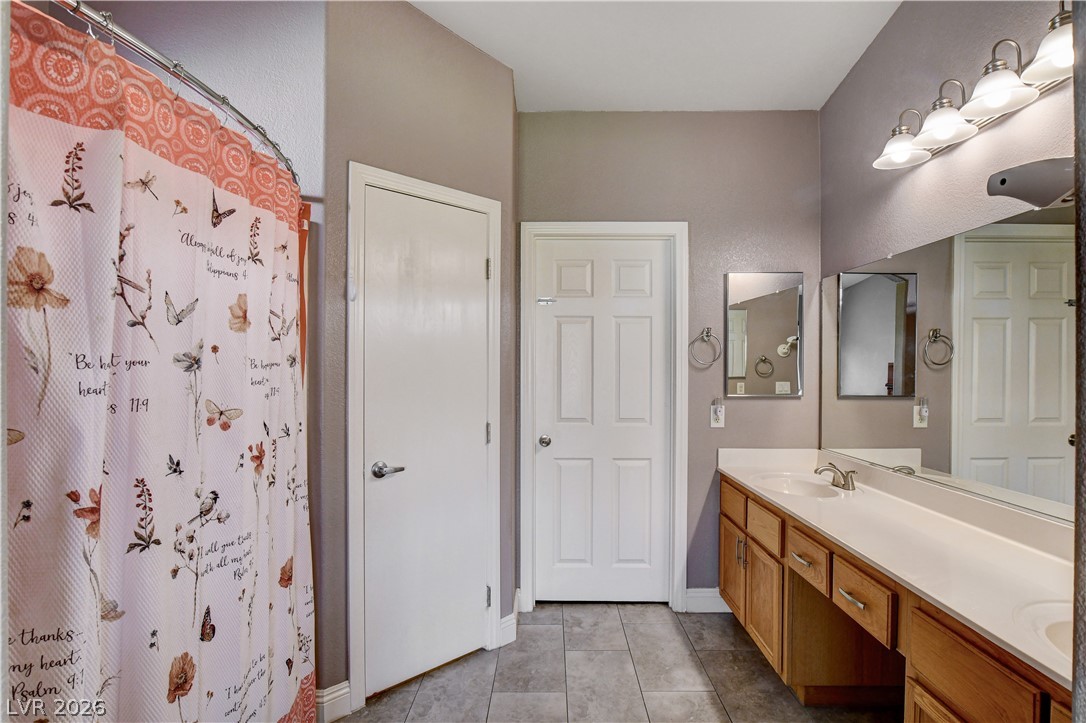 910 Cobblestone Cove Road North Las Vegas, NV 89081 - Photo 13 of 30 Double vanity, ample counter space, and tiled flooring create a practical and well-appointed bathroom.