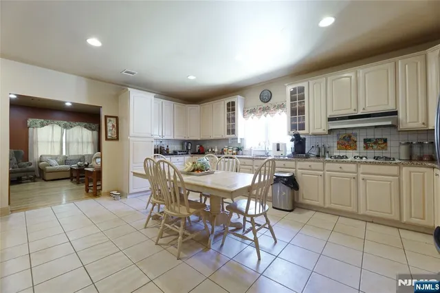 a view of a kitchen with granite countertop a refrigerator a stove a sink a dining table and chairs with wooden floor