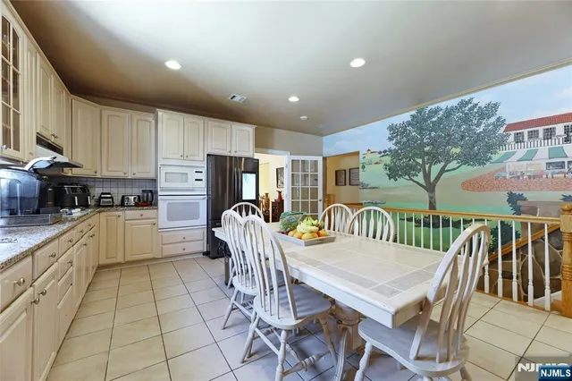 a kitchen with stainless steel appliances granite countertop a stove a sink a dining table and chairs