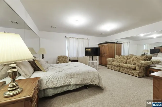 a spacious bedroom with a bed and a flat screen television