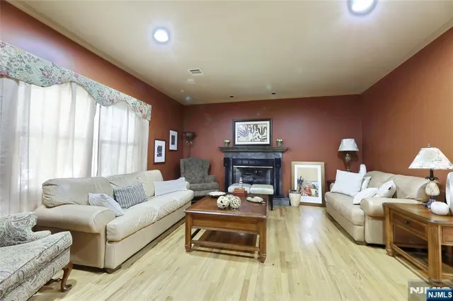 a kitchen with stainless steel appliances kitchen island granite countertop a refrigerator a stove a sink and white cabinets with wooden floor