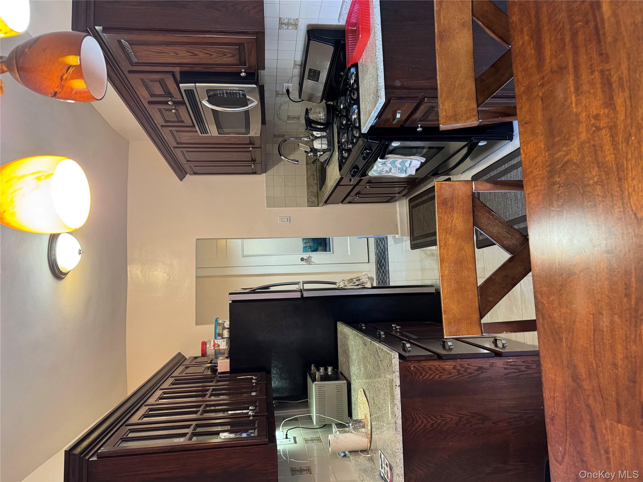 a kitchen with stainless steel appliances granite countertop a sink dishwasher a stove a refrigerator and a dining table with wooden floor