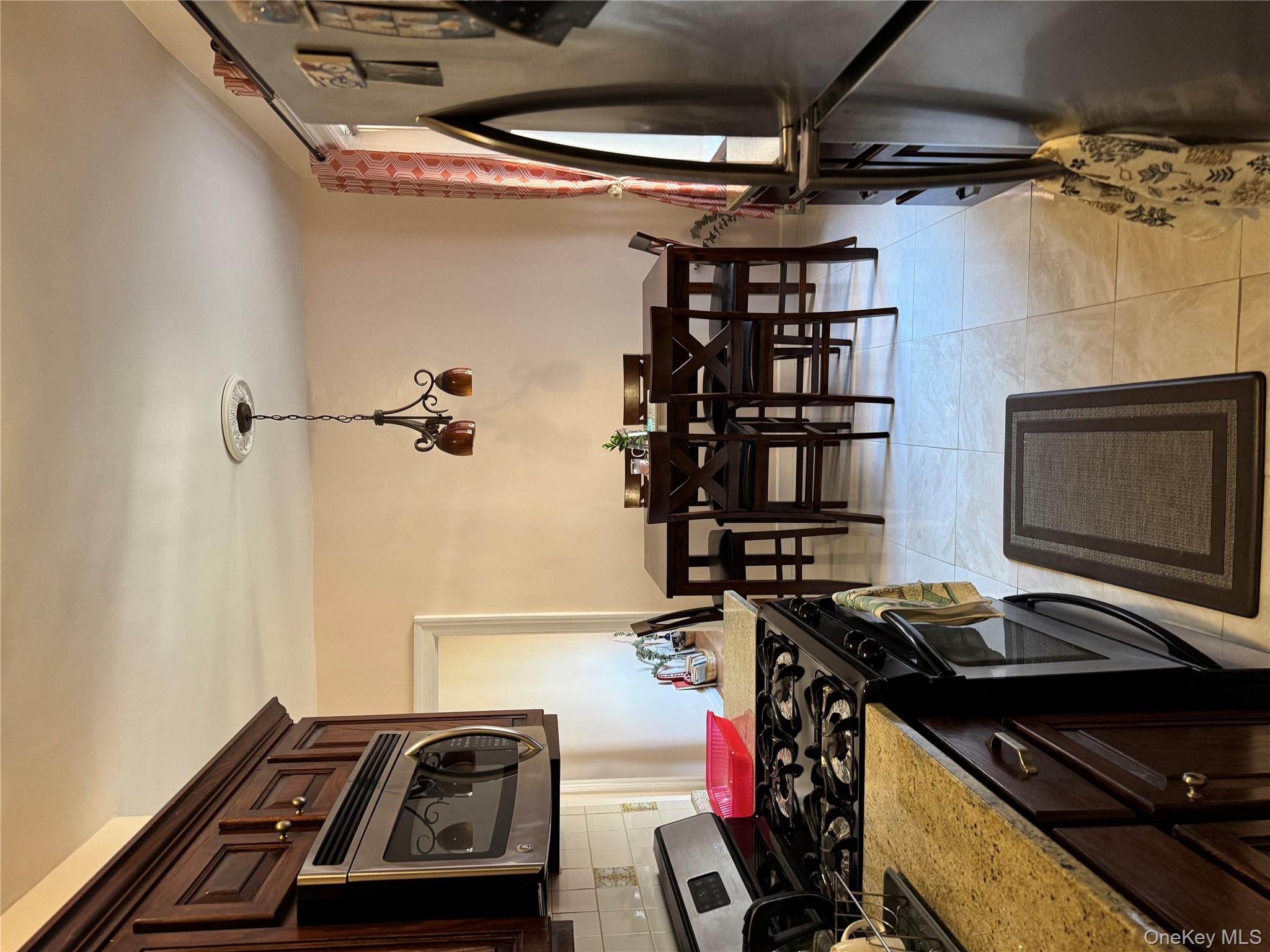 2922 Barnes Avenue, Unit 6D Bronx, NY 10467 - Photo 6 of 19 a kitchen with a stove a refrigerator and chairs