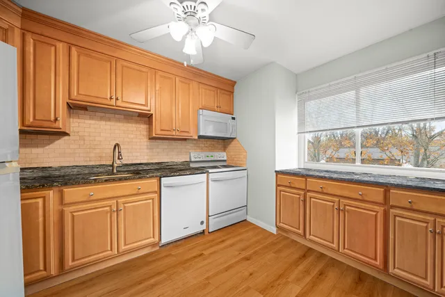 a kitchen with granite countertop stainless steel appliances sink cabinets and window