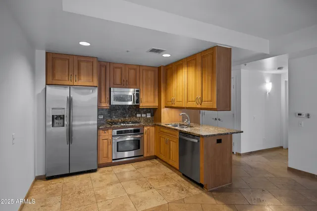 a kitchen with stainless steel appliances granite countertop a stove a refrigerator and a sink