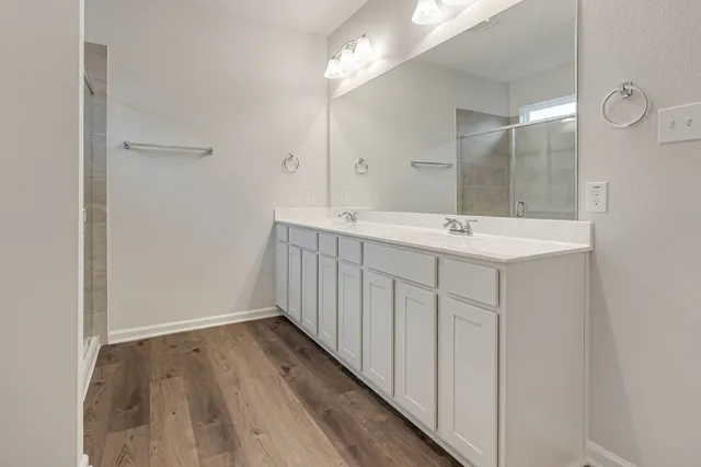 a kitchen with a stove a sink a refrigerator and white cabinets with wooden floor