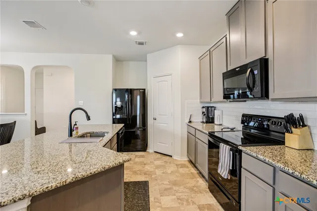 a kitchen with stainless steel appliances granite countertop a sink stove and refrigerator