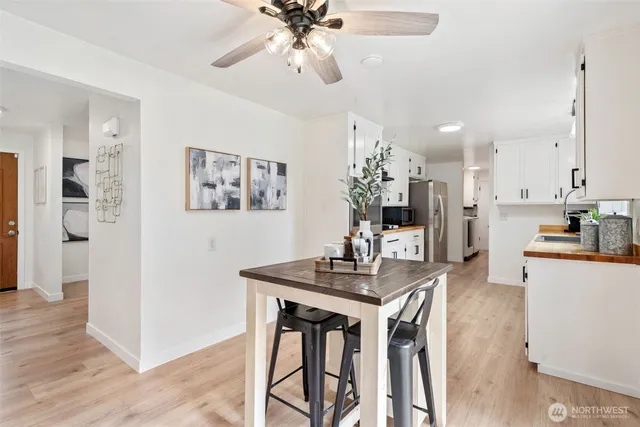 a kitchen with stainless steel appliances kitchen island granite countertop a refrigerator a stove a microwave oven with white cabinets and wooden floor